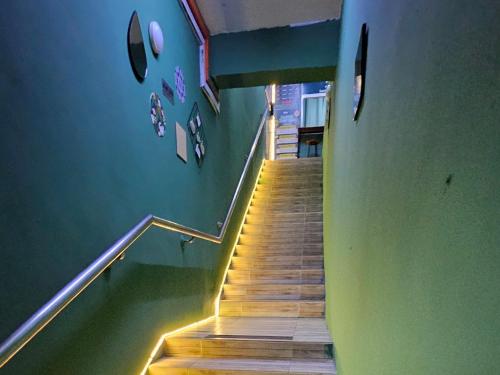 a stairway with a green wall and wooden stairs at Hotel SN Legacy in Kuala Terengganu