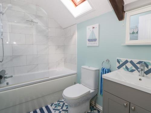 a bathroom with a toilet and a tub and a sink at Swallows Retreat in Kilgetty
