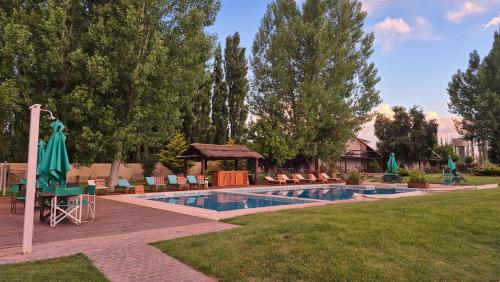 a swimming pool with chairs and a gazebo at Cabañas Amalar in Malargüe
