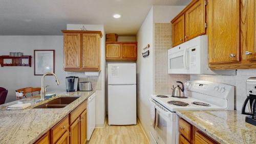 a kitchen with white appliances and wooden cabinets at Downtown McCall Condo with Balcony & Views in McCall