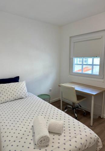 a bedroom with a bed and a desk and a window at O Refúgio dos Ferreiros in Guarda