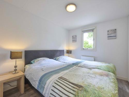 a bedroom with a bed and a lamp and a window at Vogeltrek in Kattendijke