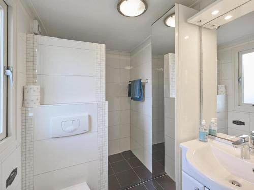 a white bathroom with a shower and a sink at Vogeltrek in Kattendijke