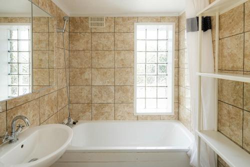 a bathroom with a tub and a sink and a window at Swingate Lane Stay in Plumstead