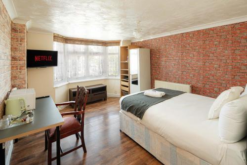 a bedroom with a bed and a brick wall at Swingate Lane Stay in Plumstead