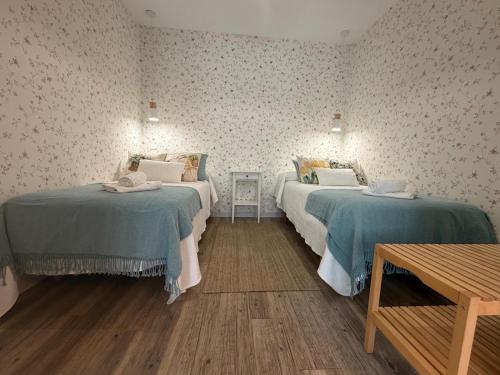 a room with two beds and a wooden table at La Puerta del Valle in Villafranca del Bierzo