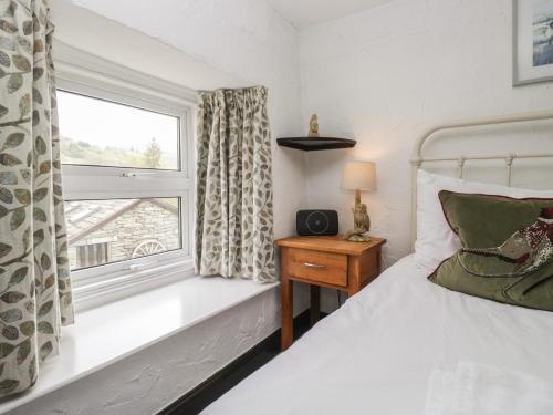 a bedroom with a bed and a window at Woodloft Cottage in Elterwater