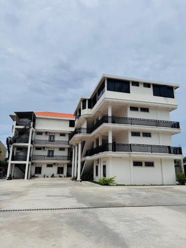 ein großes weißes Wohnhaus mit Parkplatz in der Unterkunft Leokase Hotel in Dili