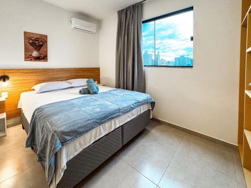 a bedroom with a bed and a large window at Centro: Flat p/ 4 pessoas + Vaga in Brusque