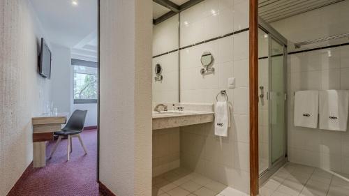 a bathroom with a sink and a shower with a mirror at Uniko Living Roma in Mexico City