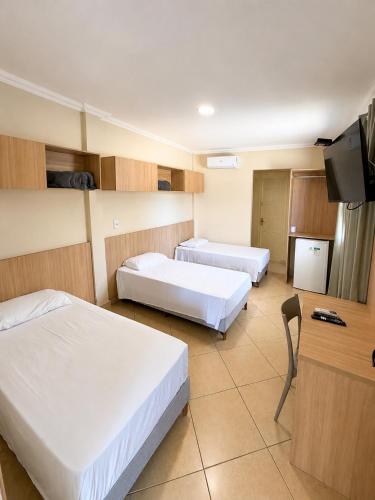a hotel room with two beds and a flat screen tv at BURITI HOTEL Barra do Riacho Aracruz in Aracruz