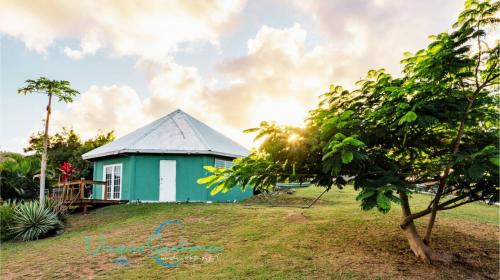 a green house on a hill with a tree at Cozy chill island roundhouse magic 2 miles from beach-The Vieques Seahouse in Moscou