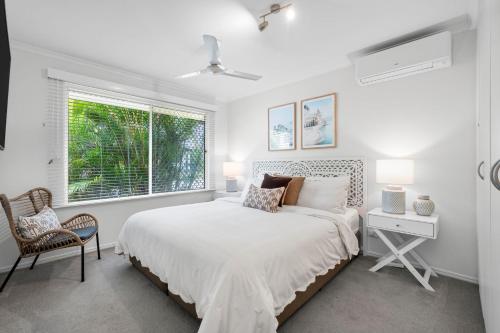 a white bedroom with a bed and a window at Renovated 2 Bedroom Ground Level Villa in Noosaville in Noosaville