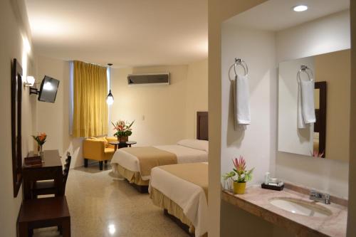 ein Hotelzimmer mit zwei Betten und einem Waschbecken in der Unterkunft Hotel Mesón de la Chinantla in San Juan Bautista Tuxtepec