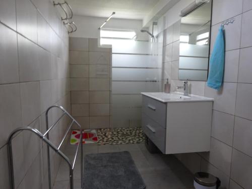 a white bathroom with a sink and a mirror at Mon Repos in Sainte-Luce