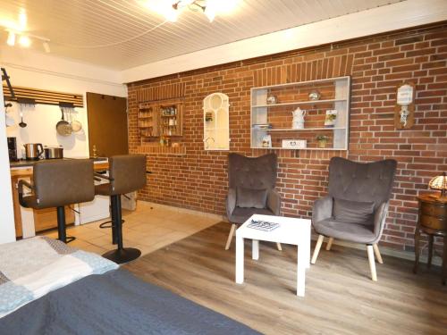 a living room with two chairs and a brick wall at fewo1846 - Hofzimmer - ländlich gelegene Auszeit für zwei Personen in Handewitt