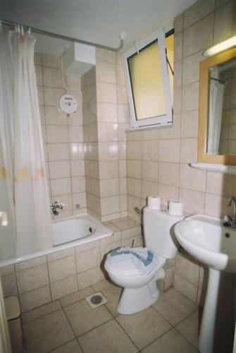 a bathroom with a toilet and a tub and a sink at Veronica Hotel in Kato Daratso