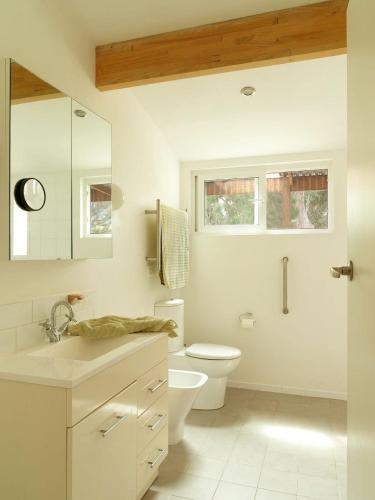 a white bathroom with a toilet and a sink at Artist's Beach House - Waterfront in Murdunna