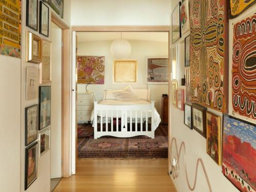 a bedroom with a white bed in a room with paintings at Artist's Beach House - Waterfront in Murdunna