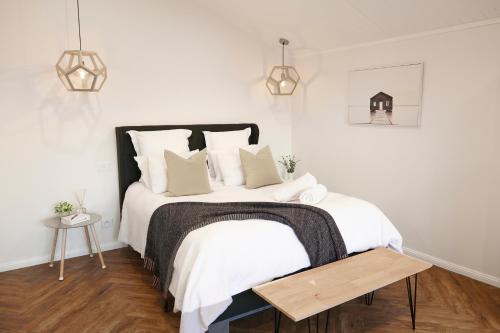 a white bedroom with a large bed with white sheets and pillows at Coco's Bungalow in Mudgee