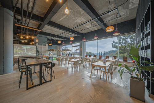 a restaurant with tables and chairs and large windows at Heyy Seogwipo Hotel in Seogwipo