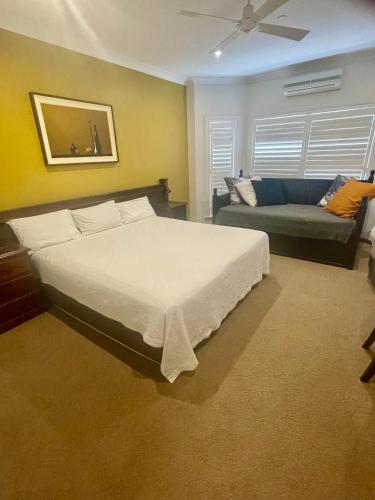 a bedroom with a large bed and a couch at Mudgee Gardens Stayz in Mudgee