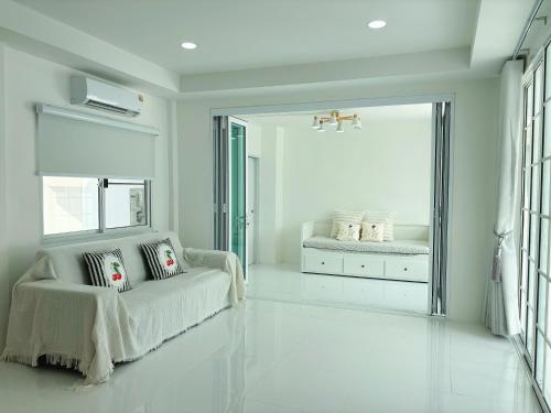 a white living room with a couch and a mirror at Whitebeach Cottage in Chon Buri