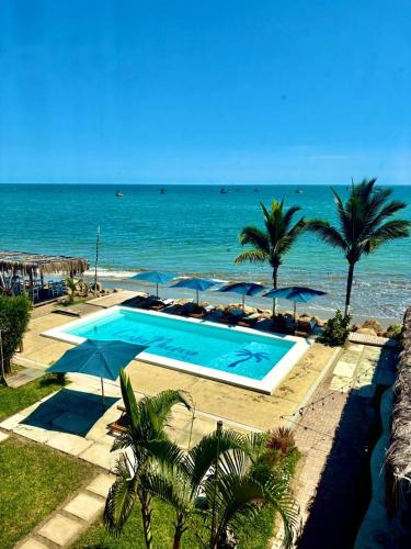 a swimming pool next to the ocean with palm trees at Costa Nueva Hotel in Zorritos