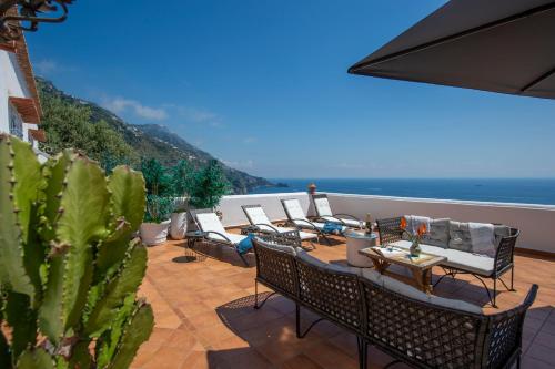 a patio with chairs and tables and a view of the ocean at Villa Algarrobos in Praiano