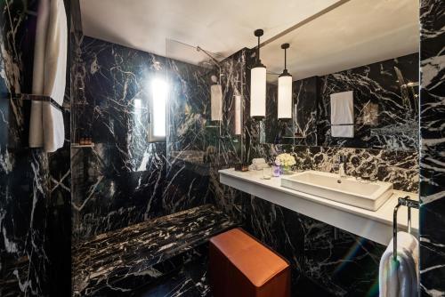 a bathroom with black marble walls and a sink at Mövenpick Hotel Mansour Eddahbi Marrakech in Marrakech