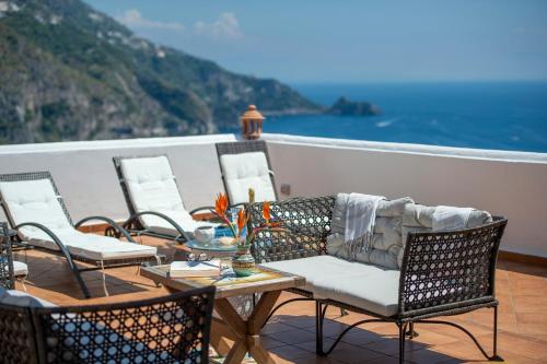 a balcony with chairs and a table and the ocean at Villa Algarrobos in Praiano