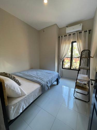 a bedroom with a bed and a ladder and a window at Casa de Lisa in Tjakranegara