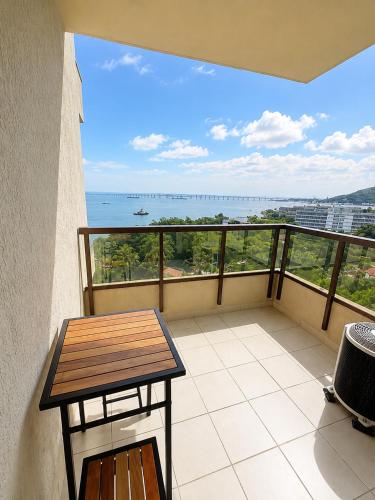 a balcony with a table and a view of the ocean at Apartamento Vista Ponte in Niterói