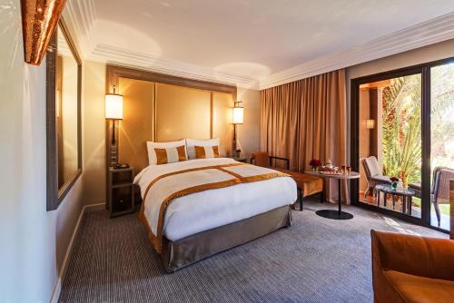 a hotel room with a large bed and a desk at Mövenpick Hotel Mansour Eddahbi Marrakech in Marrakech