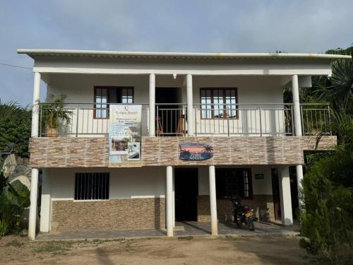 a house with a balcony and a motorcycle parked in front at Quinto Hotel in Palomino