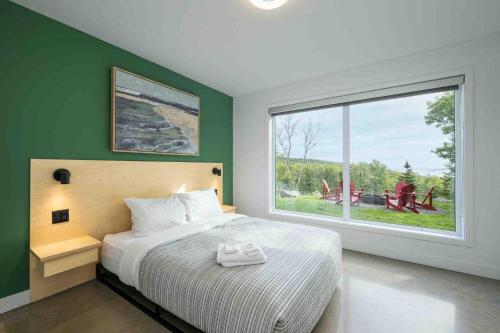 a bedroom with a bed and a large window at Käbane OPeak - Mezzanine sur le Fleuve in Les Éboulements