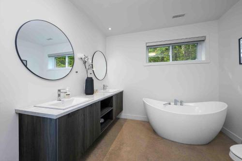 a bathroom with a tub and a sink and a mirror at Käbane OPeak - Mezzanine sur le Fleuve in Les Éboulements