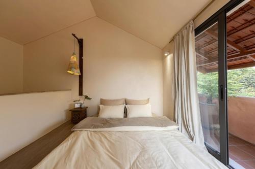 a bedroom with a bed and a large window at HiuHill House in Cồn Giả Viên