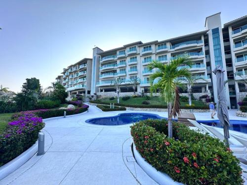 a large apartment building with a palm tree and a courtyard at B Esmeralda Pichilingue PentHouse in Acapulco