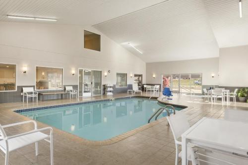 una piscina en una habitación de hotel con sillas y mesas en Country Inn & Suites by Radisson, Platteville, WI, en Platteville