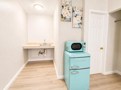 a kitchen with a blue refrigerator with a microwave on top at Royal Gateway Motel in Bend