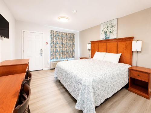 a bedroom with a bed and a desk and a window at Royal Gateway Motel in Bend