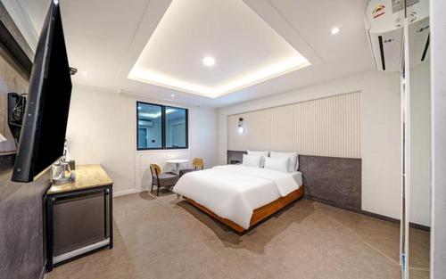 a bedroom with a white bed and a television at Hound Hotel Incheon Seogu in Incheon