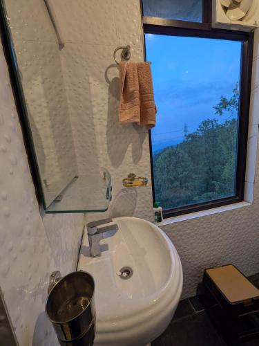 a bathroom with a white sink and a window at The Cloud Cradle in Lāhri