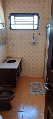 a bathroom with a sink and a toilet and a window at Casa Próxima ao Parque do Peão in Barretos
