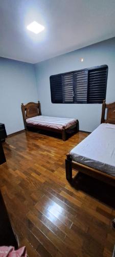 two beds in a room with wooden floors at Casa Próxima ao Parque do Peão in Barretos