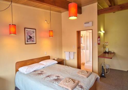 a bedroom with a bed with two towels on it at Forest Trail Lodge in Hanmer Springs