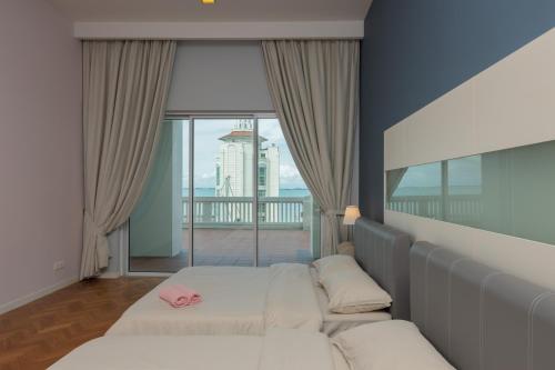 a bedroom with two beds and a large window at Straits Quay Waterside Penang in Tanjong Tokong