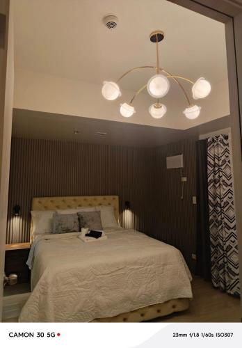 a bedroom with a large bed with a chandelier at Davao city One Lakeshore Drive at the back of sm lanang in Davao City