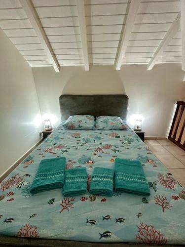 a large bed with green pillows on top of it at Le Coeur des Iles in Sainte-Anne